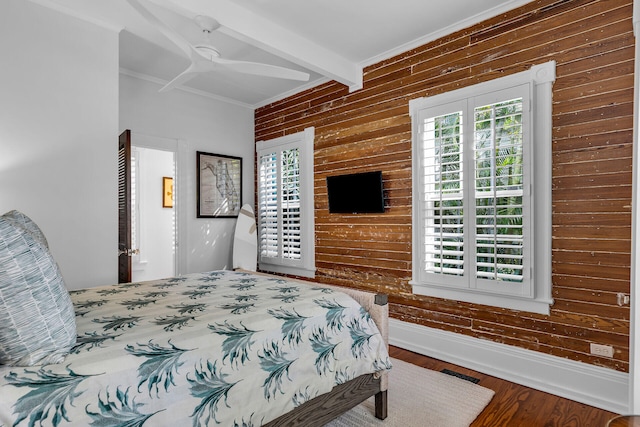 bedroom with ornamental molding, wood-type flooring, beam ceiling, and wood walls