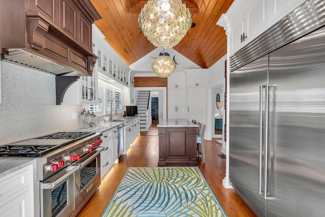 kitchen with high end appliances, decorative light fixtures, an inviting chandelier, and white cabinets