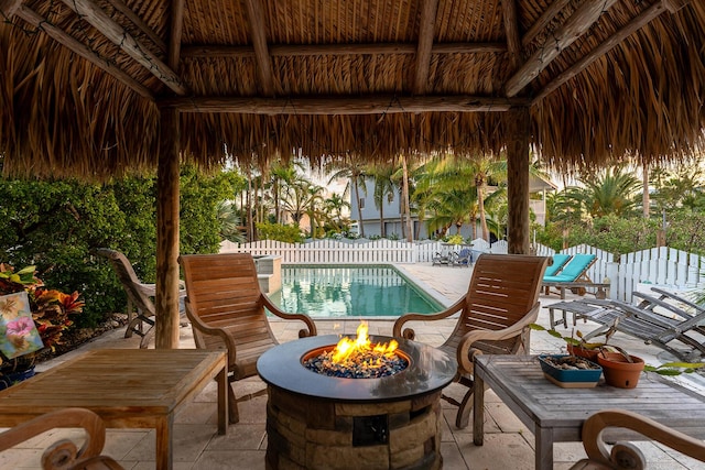 view of patio with a fenced in pool, a fire pit, and a gazebo