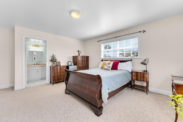 bedroom with connected bathroom, sink, and light carpet