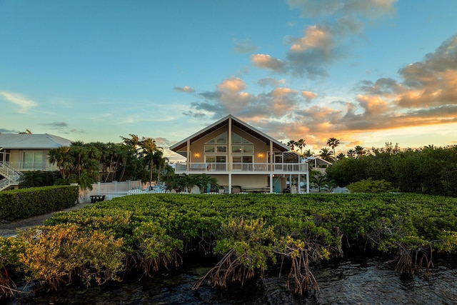 back house at dusk with a balcony and a water view