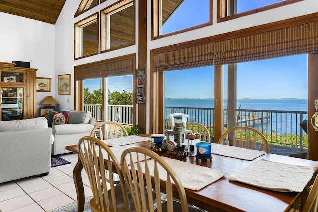 dining space featuring a water view, wood ceiling, light tile patterned flooring, and high vaulted ceiling