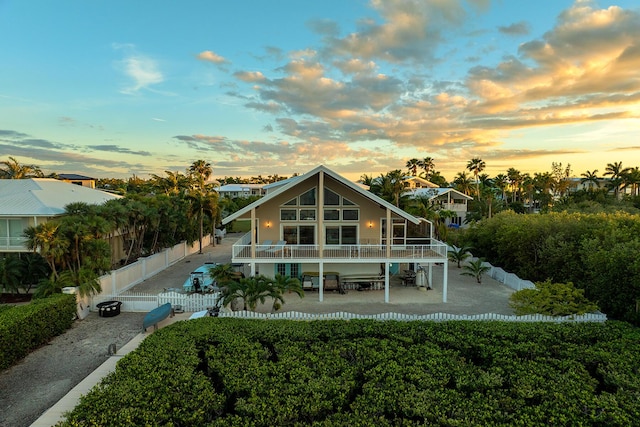 back house at dusk featuring a balcony and a patio area