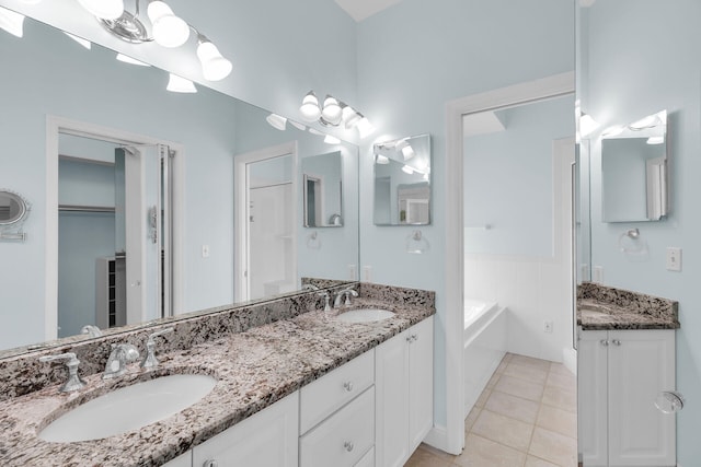 bathroom with tile patterned flooring, a garden tub, a sink, and double vanity