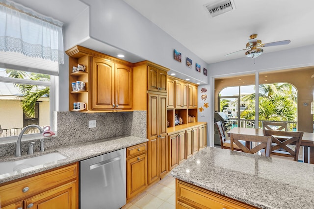 kitchen with stainless steel dishwasher, light stone countertops, sink, and backsplash