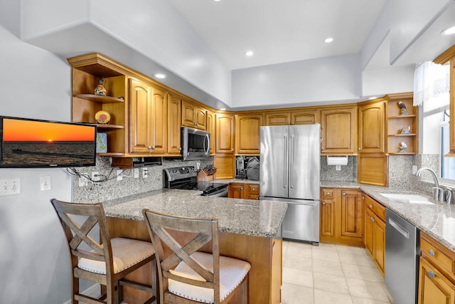 kitchen with appliances with stainless steel finishes, a breakfast bar, sink, kitchen peninsula, and light stone countertops