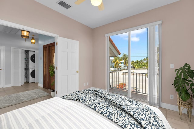 bedroom featuring light tile patterned flooring, stacked washer and clothes dryer, visible vents, and access to exterior