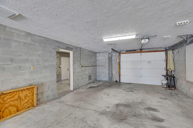 garage featuring concrete block wall and a garage door opener