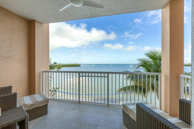 balcony featuring a water view and a ceiling fan