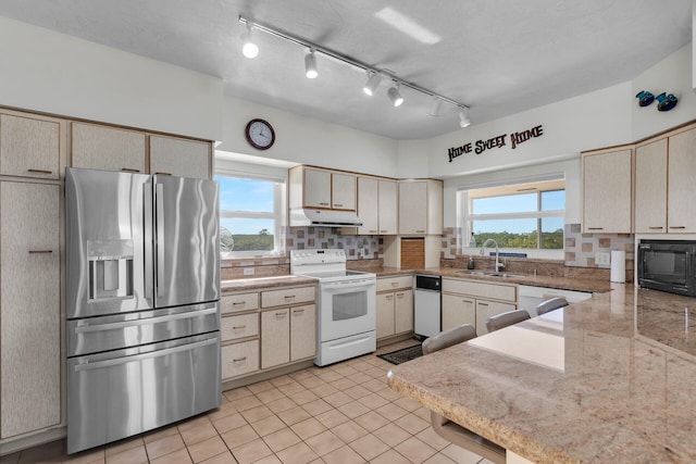 kitchen with tasteful backsplash, white appliances, a healthy amount of sunlight, and sink