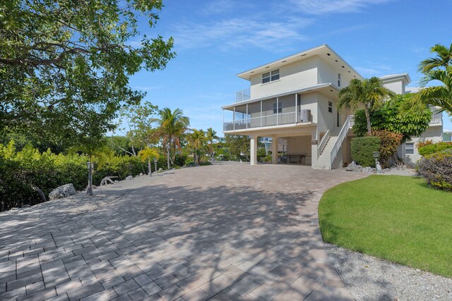 raised beach house with a carport, a sunroom, and a front lawn