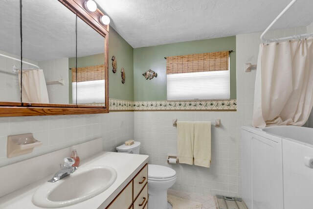 bathroom featuring plenty of natural light, tile walls, a textured ceiling, and vanity