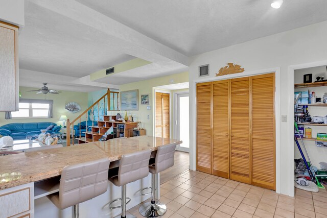 kitchen featuring a breakfast bar area, ceiling fan, and light tile patterned floors