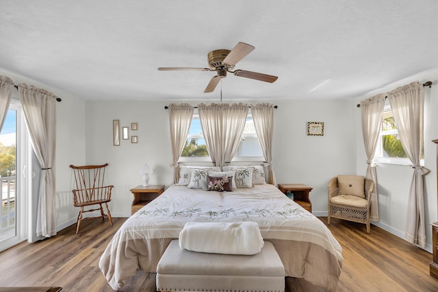 bedroom with wood-type flooring, access to outside, and ceiling fan