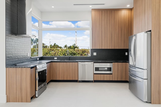 kitchen featuring appliances with stainless steel finishes, sink, dark stone countertops, and decorative backsplash
