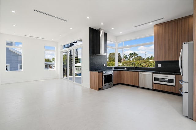 kitchen with sink, plenty of natural light, wall chimney exhaust hood, and appliances with stainless steel finishes