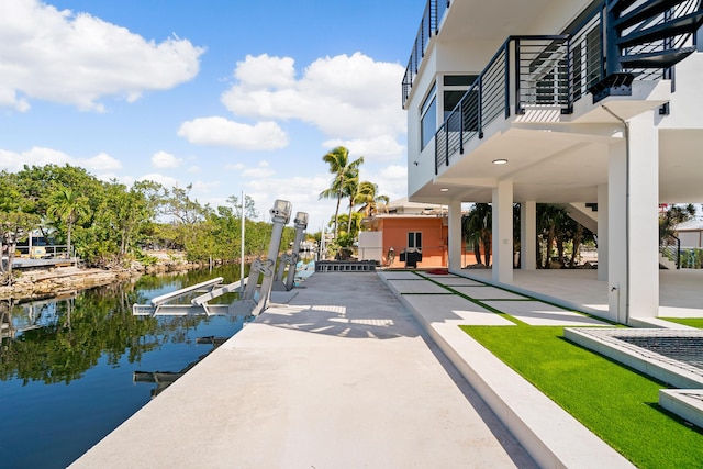 view of community with a water view, a dock, and a patio