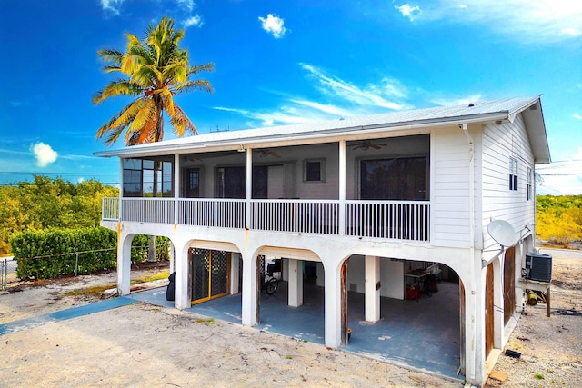 rear view of property featuring a sunroom, a ceiling fan, and central AC