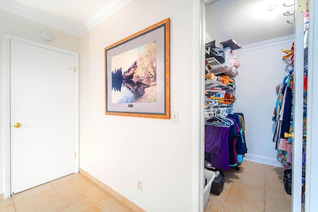 hallway with baseboards, ornamental molding, and light tile patterned flooring