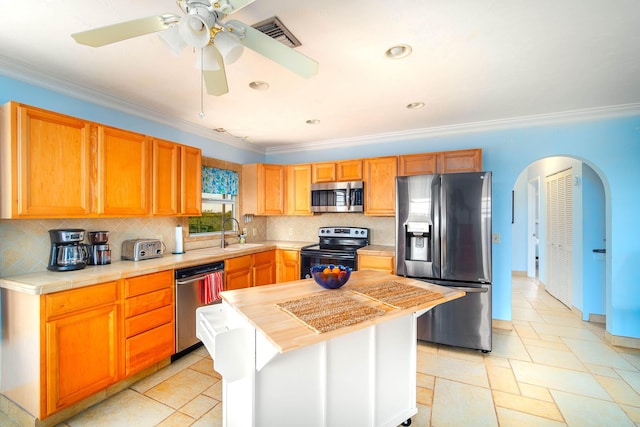 kitchen with a center island, crown molding, tasteful backsplash, visible vents, and appliances with stainless steel finishes