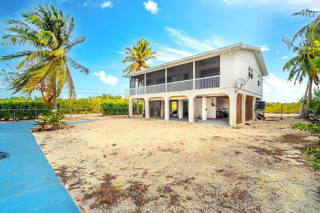 rear view of property featuring a sunroom, fence, and a carport