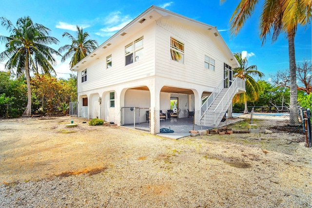 back of house featuring fence, stairway, and a patio