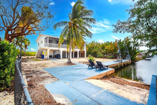 back of house with a water view, a sunroom, a patio area, and fence