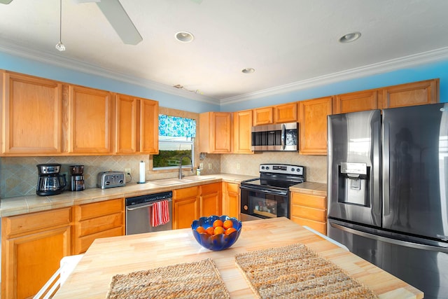 kitchen featuring tasteful backsplash, butcher block counters, ornamental molding, stainless steel appliances, and a sink