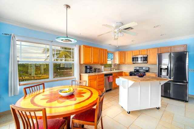 kitchen with light countertops, appliances with stainless steel finishes, backsplash, a center island, and pendant lighting