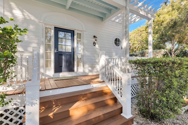 view of exterior entry with a pergola and a deck