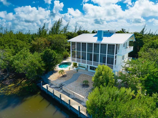 back of house featuring a water view, a swimming pool with hot tub, a patio, and a sunroom