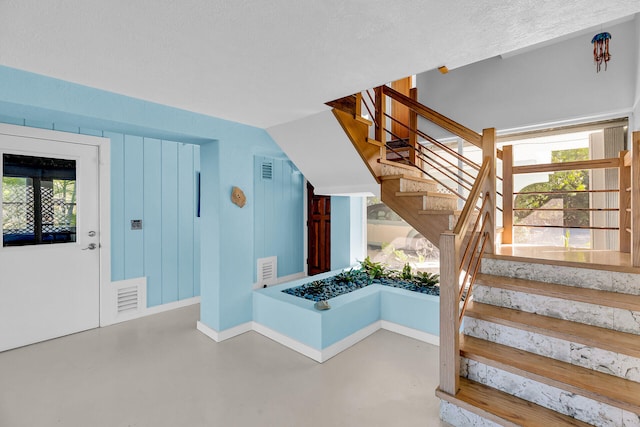 staircase featuring plenty of natural light, concrete floors, and a textured ceiling