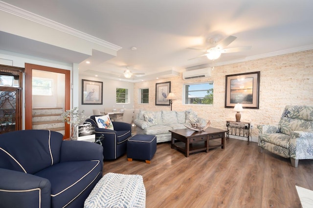 living room with crown molding, wood-type flooring, a wall unit AC, and ceiling fan