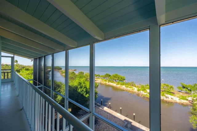 unfurnished sunroom with a water view and beamed ceiling