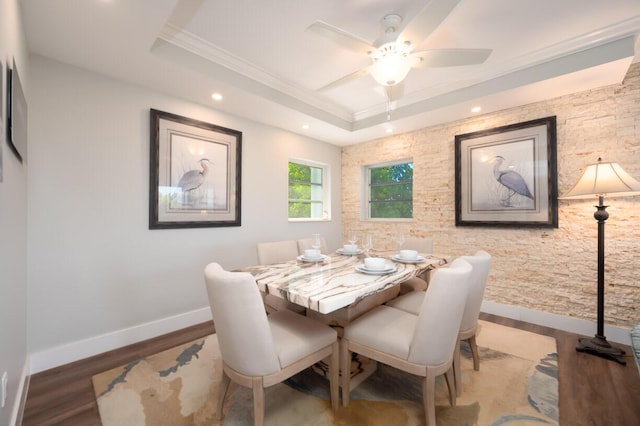 dining space with crown molding, wood-type flooring, a raised ceiling, and ceiling fan