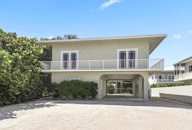 view of front facade with a carport, french doors, and a balcony