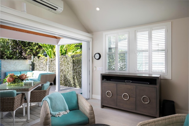 living area with lofted ceiling and a wall mounted air conditioner