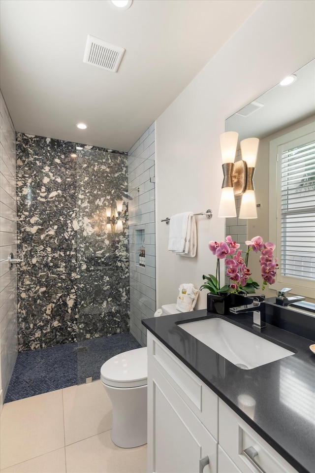 bathroom with vanity, tile patterned floors, toilet, and tiled shower