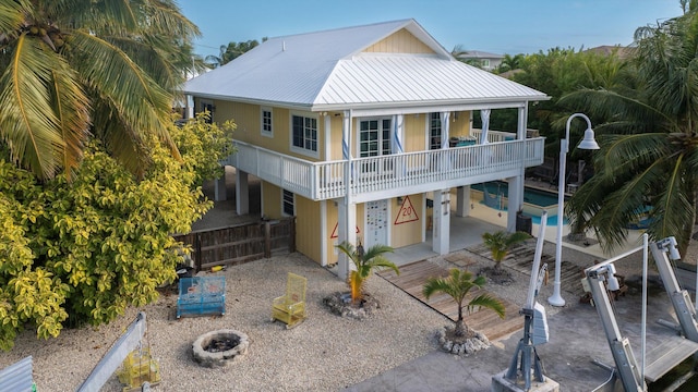 rear view of property with a fire pit, a patio, and a balcony