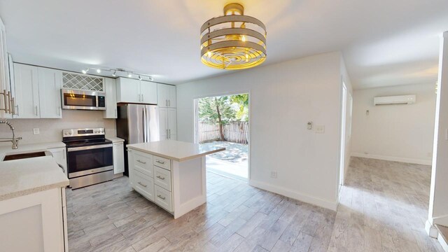 kitchen featuring stainless steel appliances, a center island, sink, and white cabinets