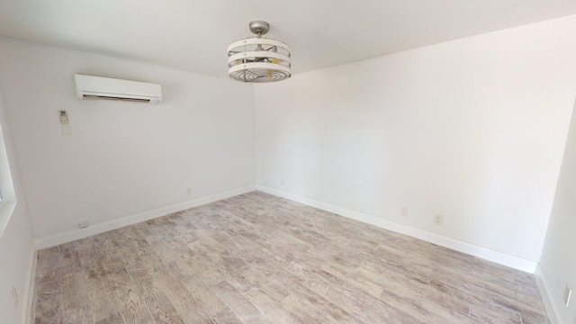 empty room with light wood-type flooring and an AC wall unit