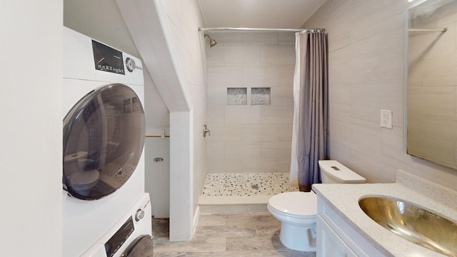 bathroom featuring vanity, toilet, curtained shower, and stacked washing maching and dryer