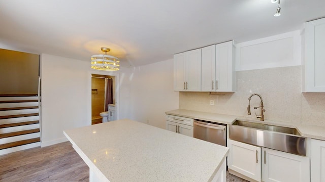 kitchen featuring stainless steel dishwasher, sink, hanging light fixtures, and white cabinets