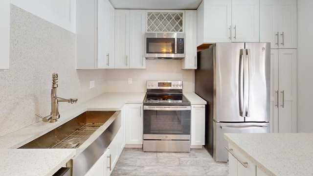 kitchen featuring white cabinetry, appliances with stainless steel finishes, light stone countertops, and sink