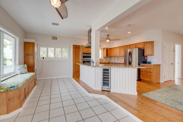 kitchen featuring ceiling fan, backsplash, light stone countertops, kitchen peninsula, and beverage cooler