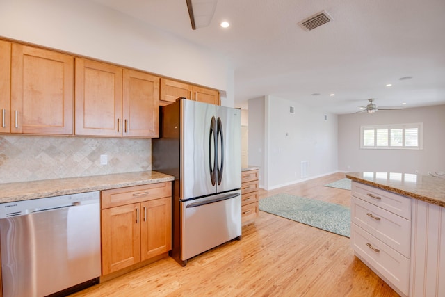 kitchen featuring light stone counters, light brown cabinets, appliances with stainless steel finishes, light hardwood / wood-style floors, and decorative backsplash