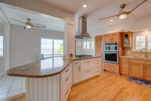 kitchen featuring sink, ceiling fan, appliances with stainless steel finishes, white cabinetry, and island exhaust hood