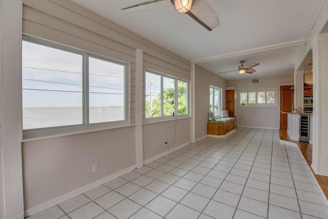 unfurnished sunroom featuring beverage cooler, ceiling fan, and a water view