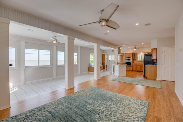 unfurnished living room with decorative columns, ceiling fan, and light hardwood / wood-style floors