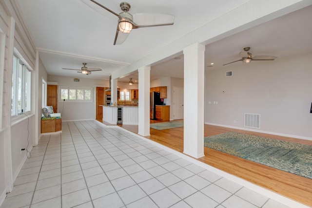 interior space with light tile patterned floors, ceiling fan, and ornate columns